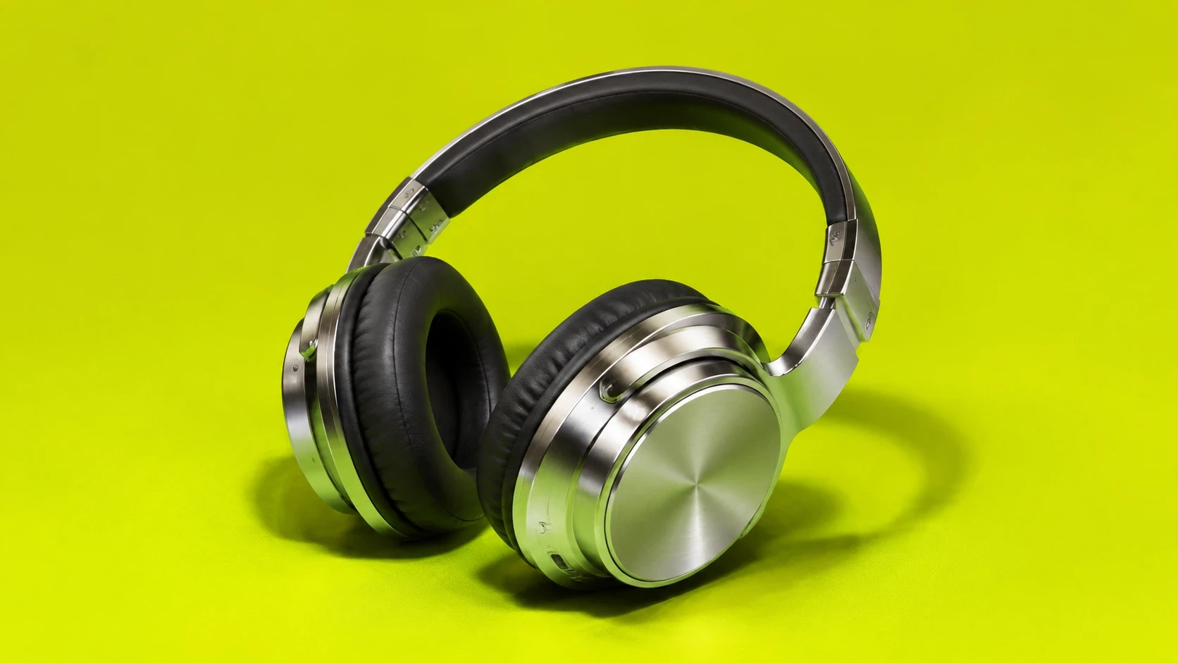 Auriculares AURA de metal cepillado apoyados sobre un fondo de estudio, en blanco y negro