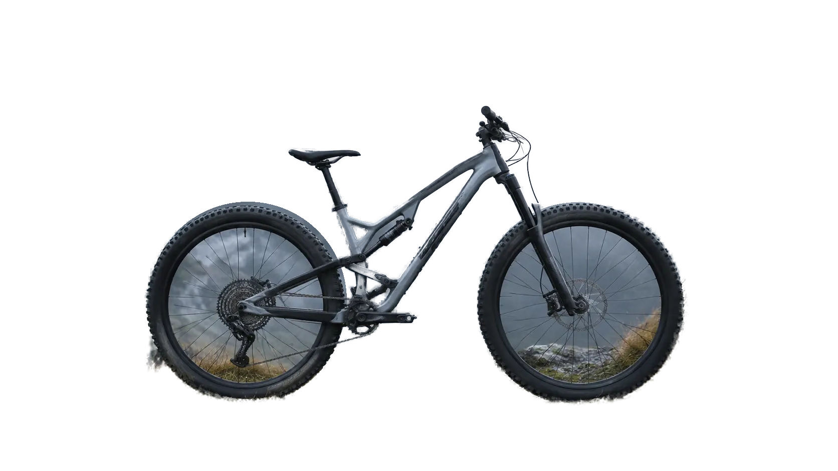 Bicicleta Ridge de perfil, apoyada sobre roca frente a montañas con niebla
